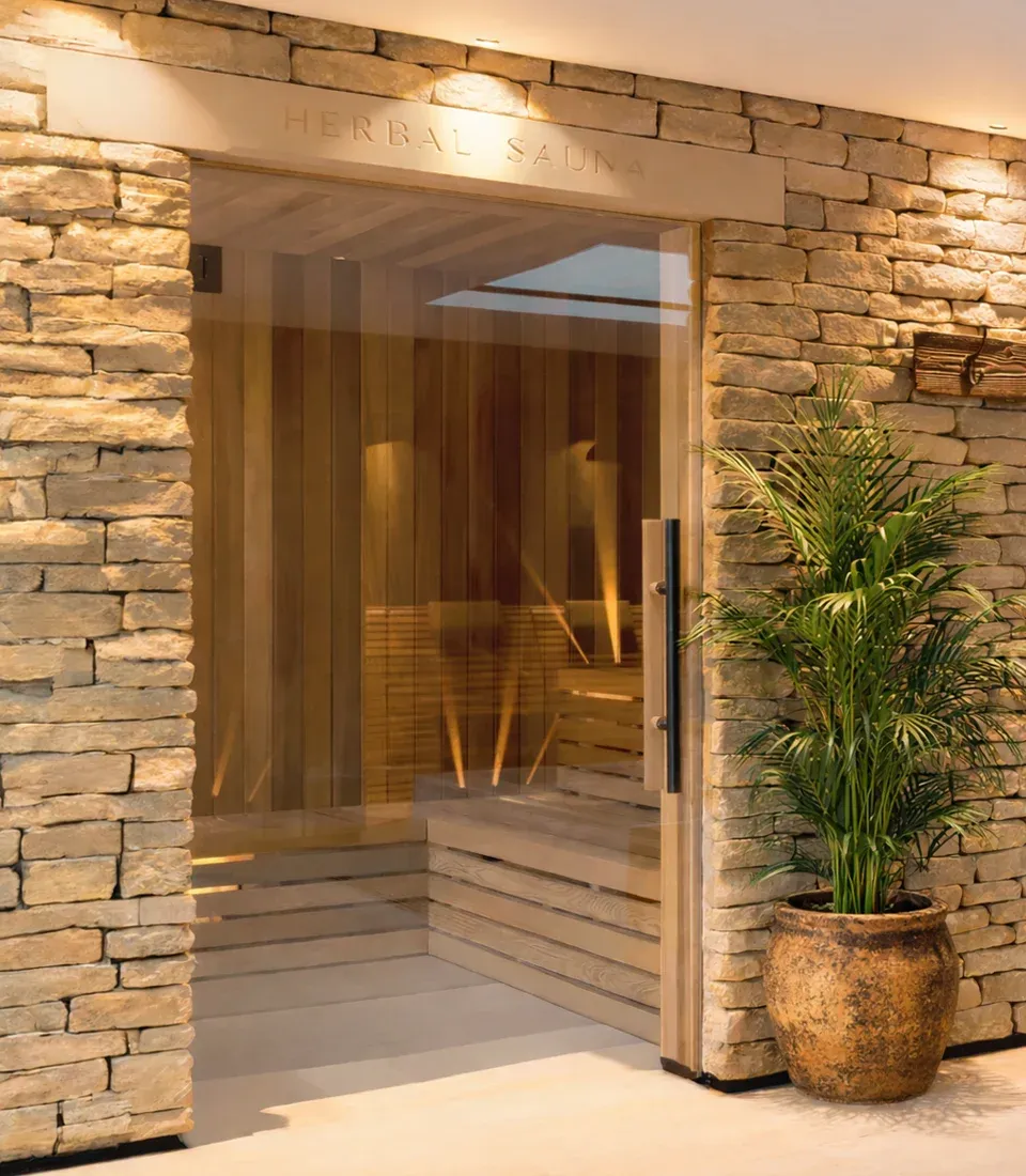 Homefield Grange herbal sauna with glass entrance, stone wall and natural timber interior
